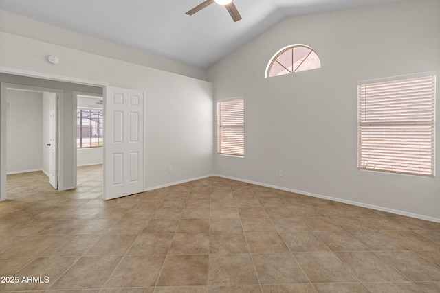 empty room with baseboards, ceiling fan, light tile patterned floors, and high vaulted ceiling
