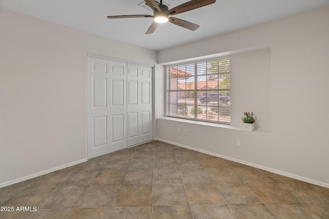 unfurnished bedroom featuring baseboards, ceiling fan, a closet, and tile patterned floors