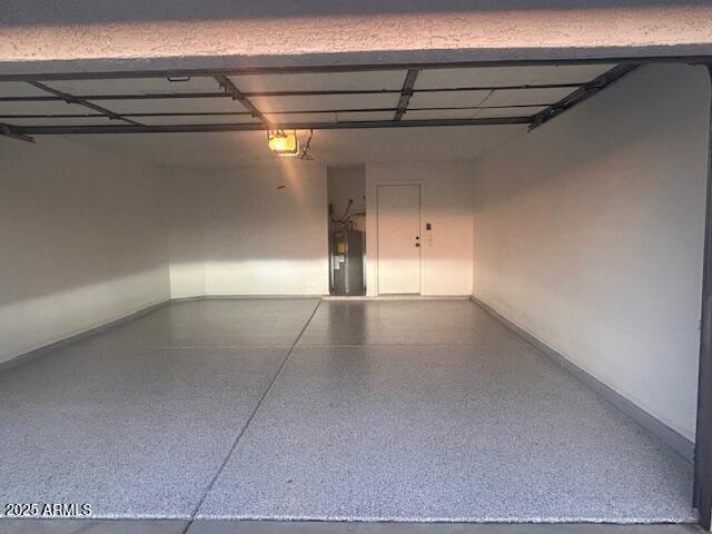 garage featuring water heater, baseboards, and a garage door opener