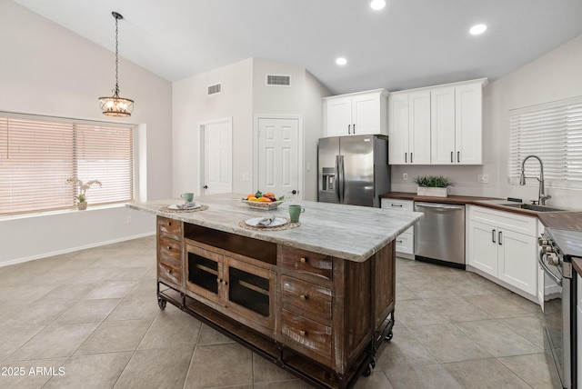 kitchen featuring vaulted ceiling, stainless steel appliances, a sink, and visible vents