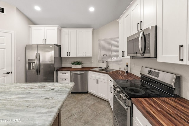 kitchen featuring a sink, butcher block countertops, stainless steel appliances, white cabinetry, and recessed lighting