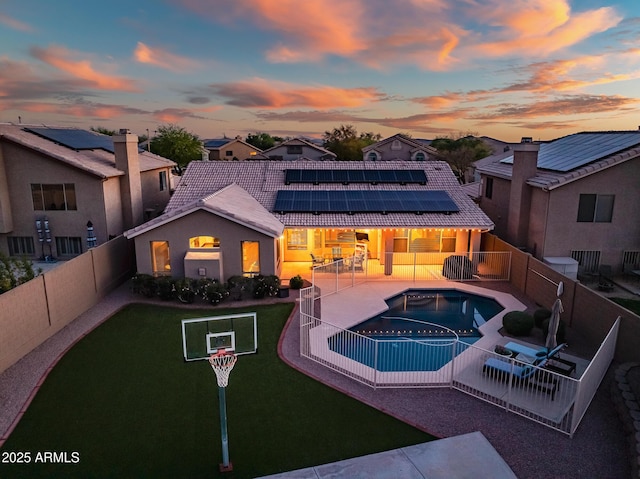 exterior space featuring roof mounted solar panels, a lawn, a fenced backyard, a tile roof, and a patio