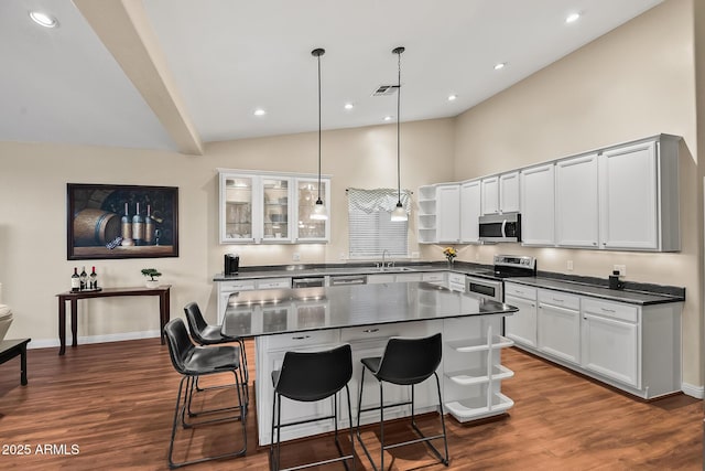 kitchen featuring a kitchen bar, dark countertops, open shelves, and stainless steel appliances