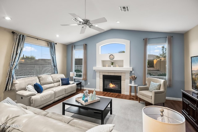 living area featuring visible vents, a tile fireplace, vaulted ceiling, and wood finished floors