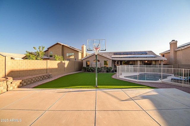 view of basketball court with a fenced backyard and a lawn