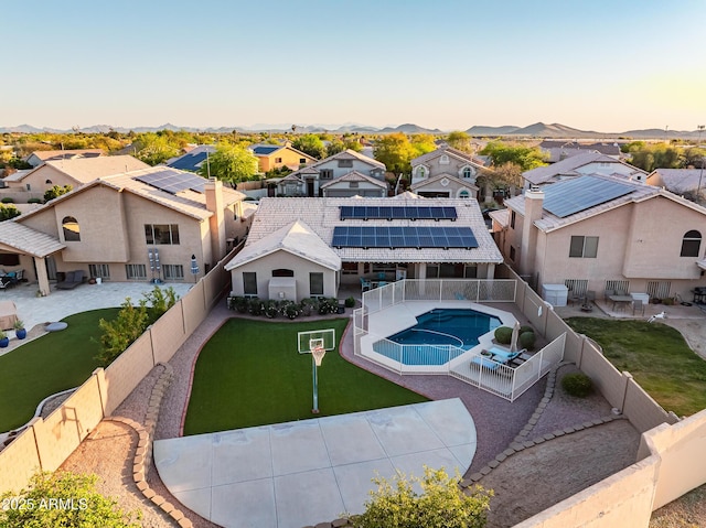 back of house at dusk featuring a patio area, a fenced backyard, a fenced in pool, and a residential view