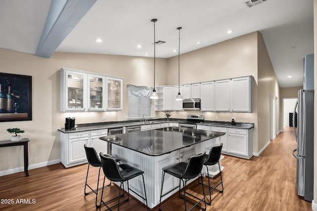 kitchen with a kitchen breakfast bar, dark countertops, a sink, stainless steel appliances, and baseboards