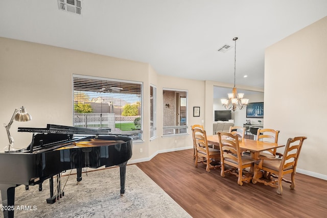 dining area featuring a notable chandelier, visible vents, baseboards, and wood finished floors