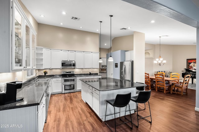kitchen featuring light wood finished floors, a kitchen island, visible vents, and stainless steel appliances