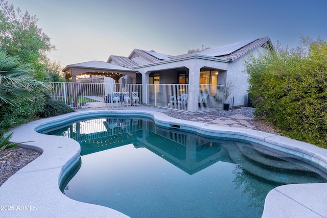 pool at dusk with a gazebo and a patio area