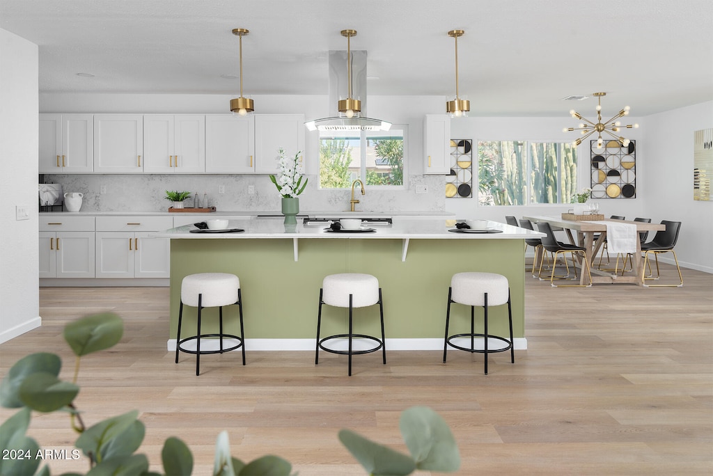 kitchen with light hardwood / wood-style floors, white cabinetry, hanging light fixtures, and a kitchen bar