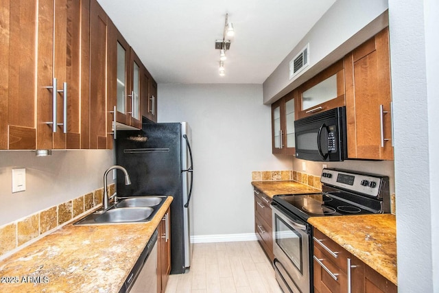 kitchen with light stone counters, rail lighting, appliances with stainless steel finishes, and sink