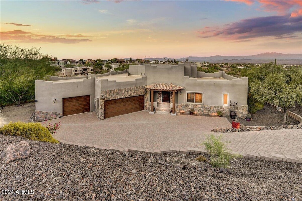 pueblo-style home with a garage and a mountain view