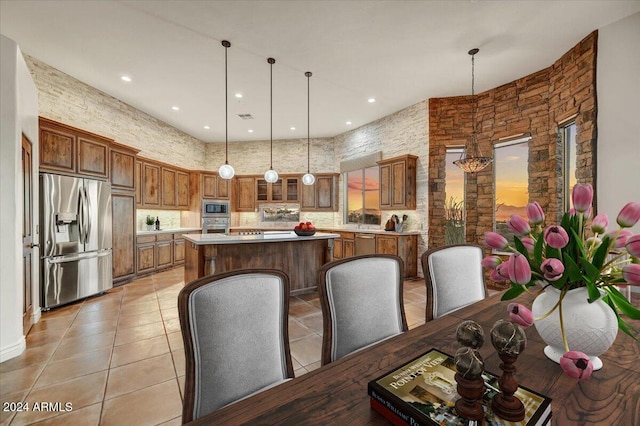 kitchen with stainless steel appliances, hanging light fixtures, light tile patterned floors, and a center island