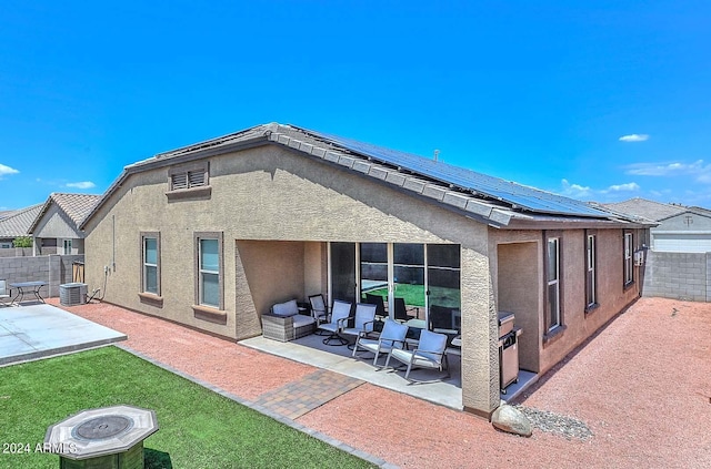 rear view of house featuring roof mounted solar panels, a patio area, a fenced backyard, and stucco siding