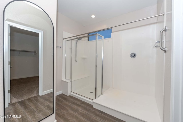 bathroom featuring a spacious closet, baseboards, wood finish floors, recessed lighting, and a stall shower