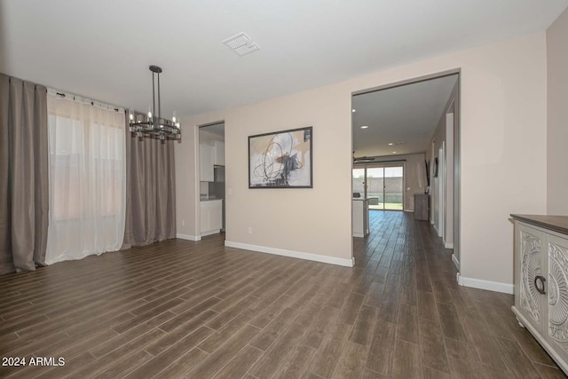 unfurnished dining area featuring visible vents, baseboards, a notable chandelier, and dark wood finished floors