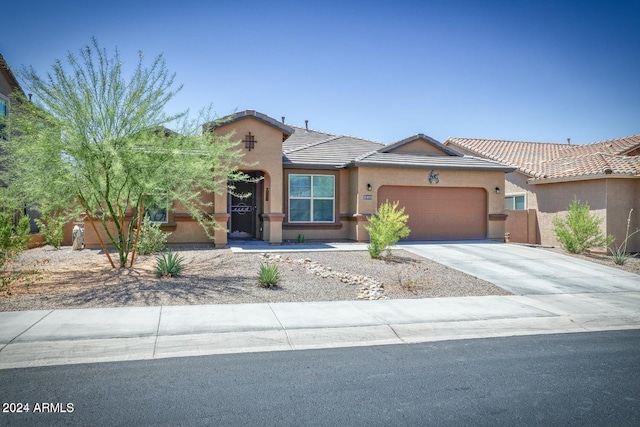 view of front of house featuring a tile roof, an attached garage, driveway, and stucco siding