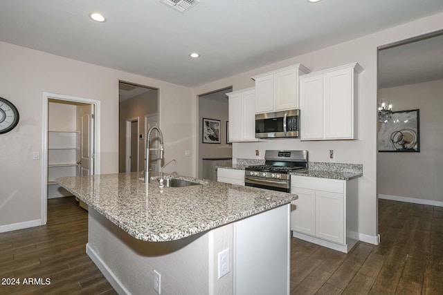 kitchen featuring visible vents, a kitchen island with sink, a sink, dark wood-type flooring, and appliances with stainless steel finishes