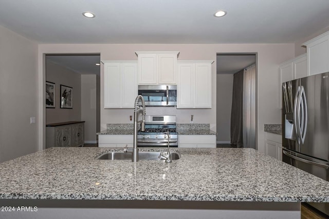 kitchen with a sink, light stone counters, white cabinetry, recessed lighting, and stainless steel appliances