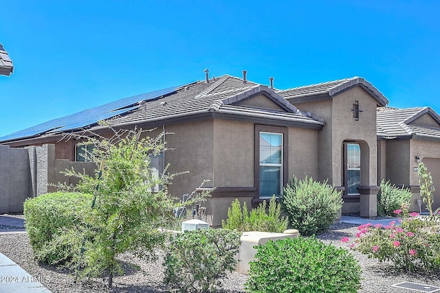 exterior space with roof mounted solar panels, stucco siding, and a tiled roof