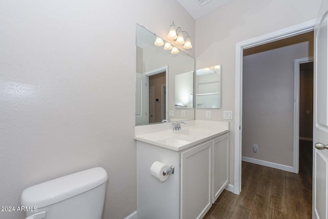 bathroom with vanity, toilet, wood finished floors, and baseboards