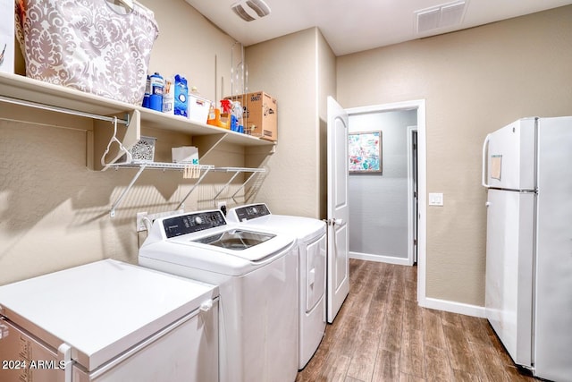 clothes washing area with visible vents, light wood-style floors, laundry area, and washing machine and clothes dryer