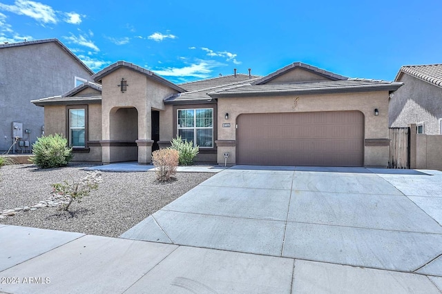 view of front of home with fence, a tile roof, concrete driveway, stucco siding, and a garage