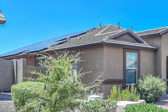 view of property exterior with solar panels, a tiled roof, and stucco siding