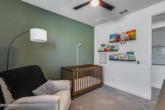 carpeted bedroom featuring a nursery area and ceiling fan