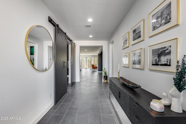 hallway featuring a barn door and dark tile patterned flooring