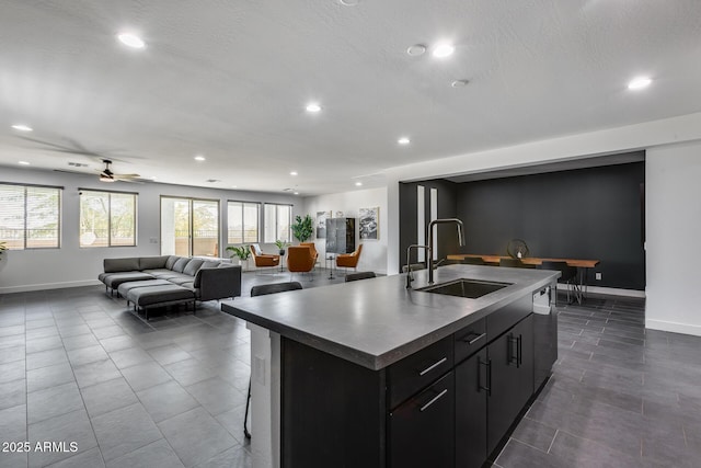 kitchen with sink, black dishwasher, an island with sink, and dark tile patterned flooring