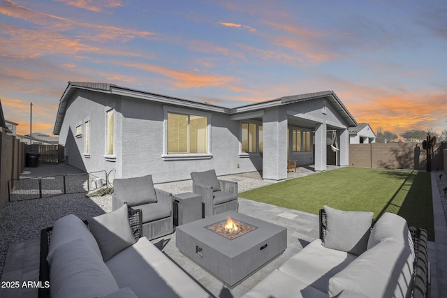 back house at dusk with a lawn, an outdoor living space with a fire pit, and a patio area