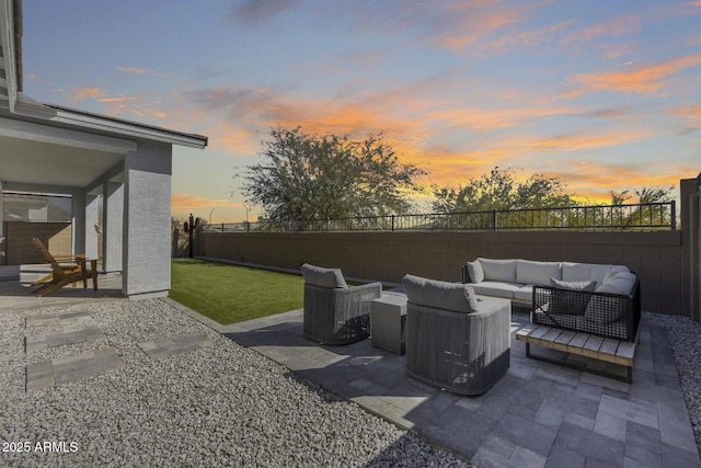 patio terrace at dusk featuring an outdoor living space and a lawn