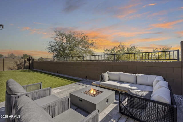 patio terrace at dusk with a lawn and an outdoor living space with a fire pit