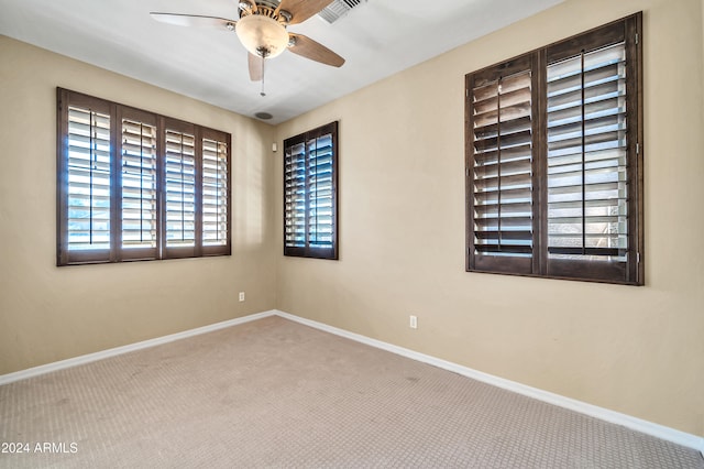 carpeted spare room featuring ceiling fan and plenty of natural light