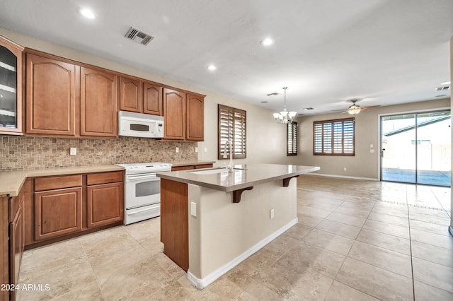 kitchen with decorative backsplash, sink, an island with sink, pendant lighting, and white appliances