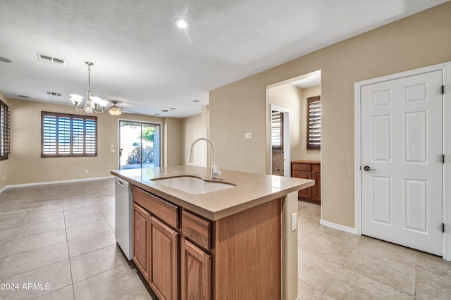 kitchen with sink, white dishwasher, light tile patterned floors, an island with sink, and hanging light fixtures