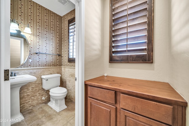 bathroom with toilet and tile walls