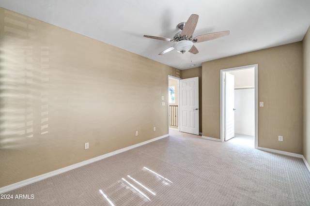 unfurnished bedroom with a spacious closet, light carpet, and ceiling fan