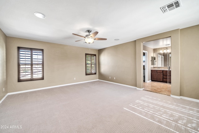 empty room featuring ceiling fan, plenty of natural light, and light carpet