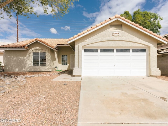 view of front of home featuring a tiled roof, stucco siding, driveway, and a garage