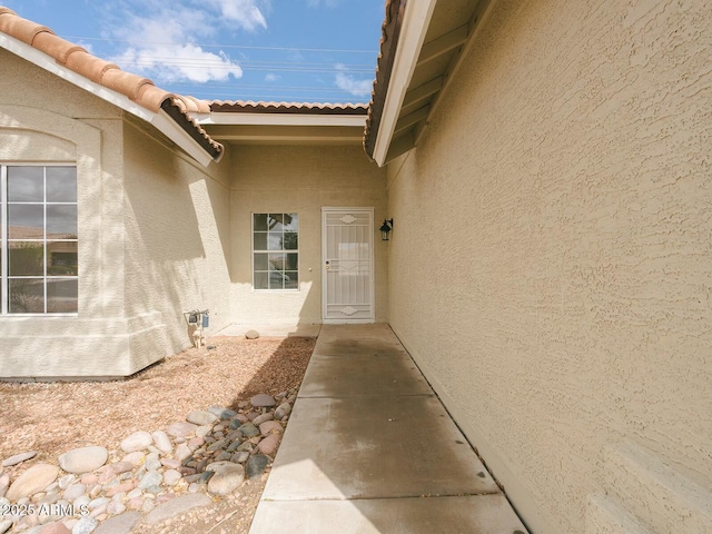 entrance to property with stucco siding and a tiled roof