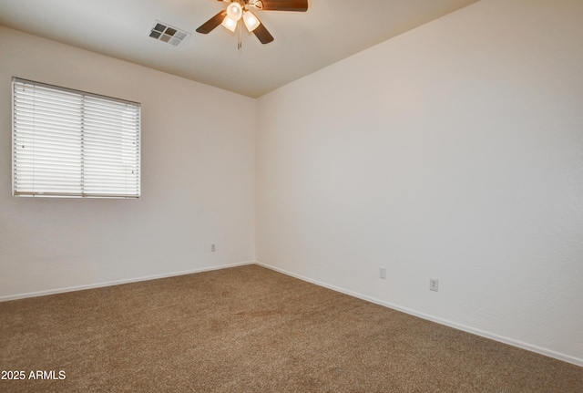 carpeted spare room with baseboards, a ceiling fan, and visible vents