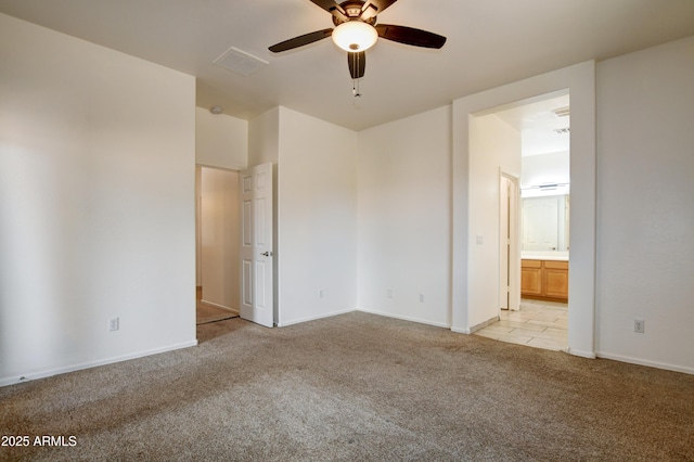 unfurnished bedroom featuring light carpet, ensuite bath, a ceiling fan, baseboards, and visible vents