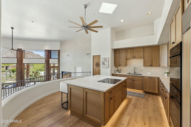 11334 E Troon Vista Dr, Scottsdale, AZ 85255 - kitchen featuring black electric cooktop, a ceiling fan, a sink, light wood-type flooring, and a kitchen island