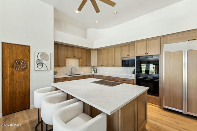 11334 E Troon Vista Dr, Scottsdale, AZ 85255 - kitchen featuring a sink, black appliances, a breakfast bar area, light countertops, and a kitchen island
