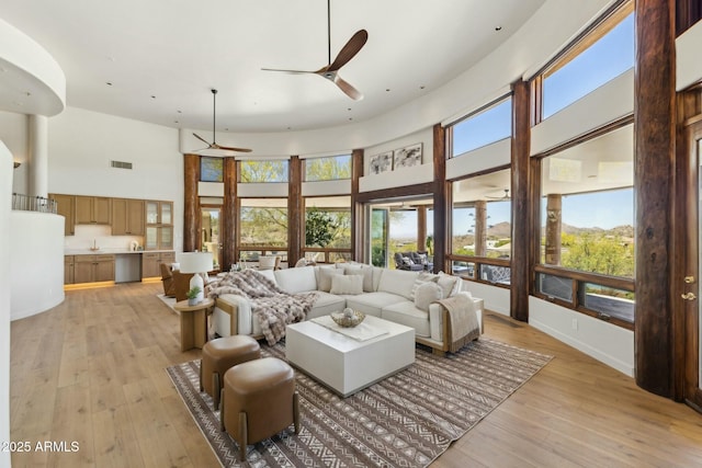 11334 E Troon Vista Dr, Scottsdale, AZ 85255 - living room featuring visible vents, baseboards, light wood-style floors, a high ceiling, and ceiling fan