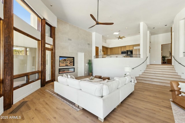 11334 E Troon Vista Dr, Scottsdale, AZ 85255 - living area featuring a ceiling fan, light wood-type flooring, a towering ceiling, a tiled fireplace, and visible vents