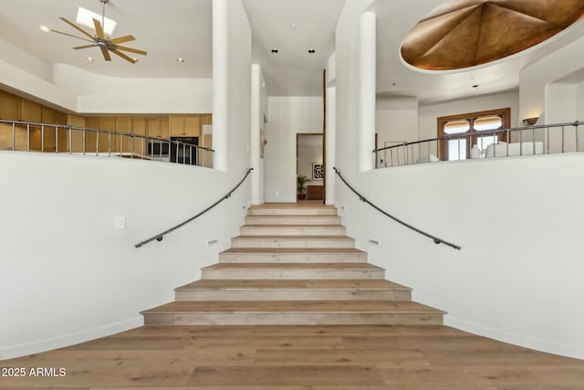 11334 E Troon Vista Dr, Scottsdale, AZ 85255 - staircase featuring wood finished floors, a ceiling fan, and a towering ceiling